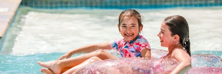 people swimming and splashing in outdoor pool